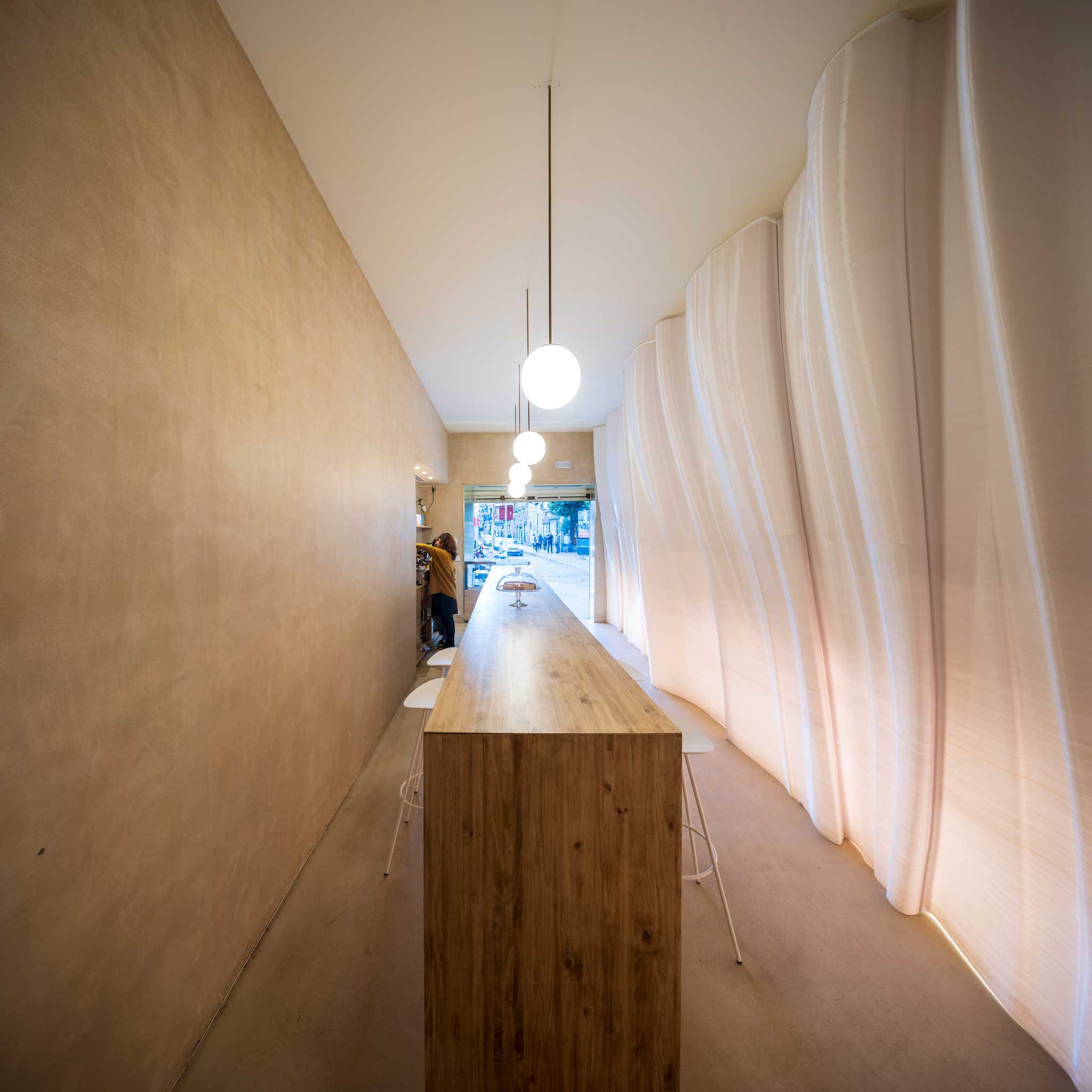 Espacio longitudinal del local con geometrías curvas diseñadas por Estudio RRR y fabricadas con impresión 3D de gran formato.